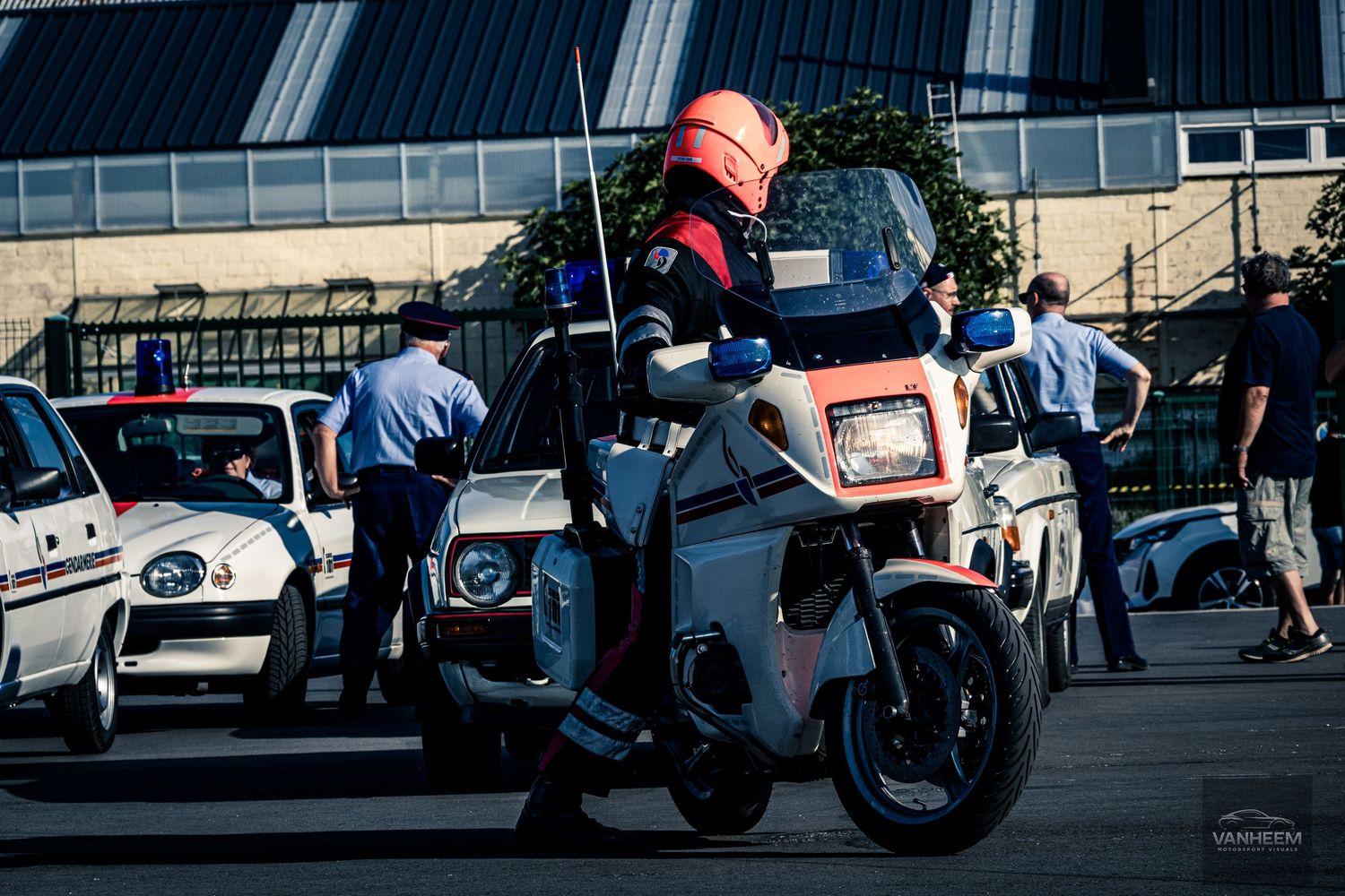 A row of vintage motorcycles and cars parked at a classic vehicle show during daytime.