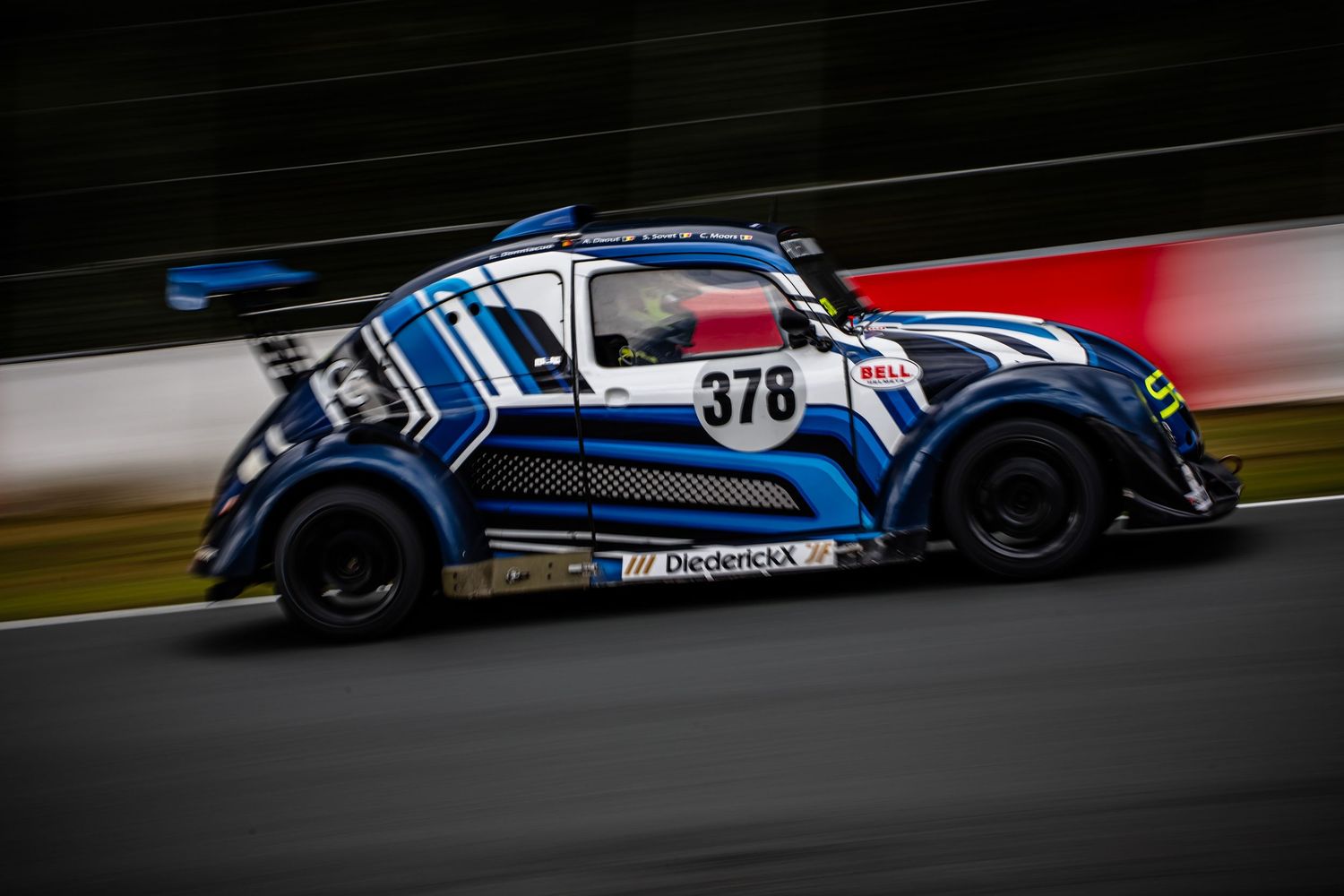 Blue and white race car #378 with DiepenCKX livery speeding around a wet racing circuit track.