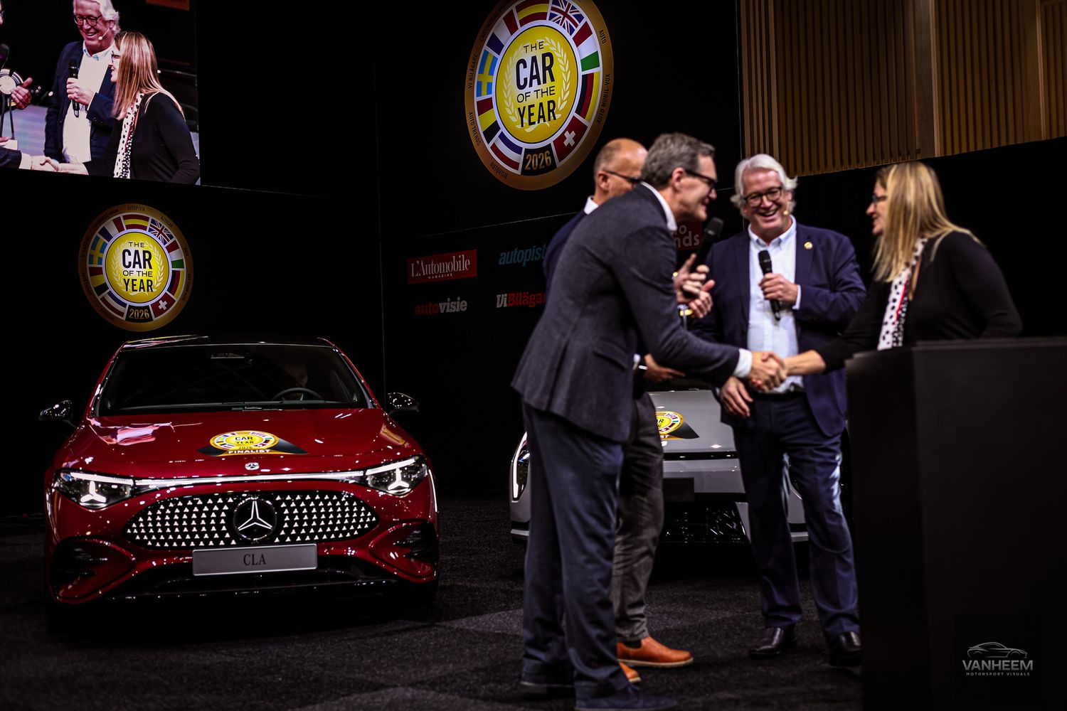 Classic red Chevrolet car displayed at formal auto show presentation event.