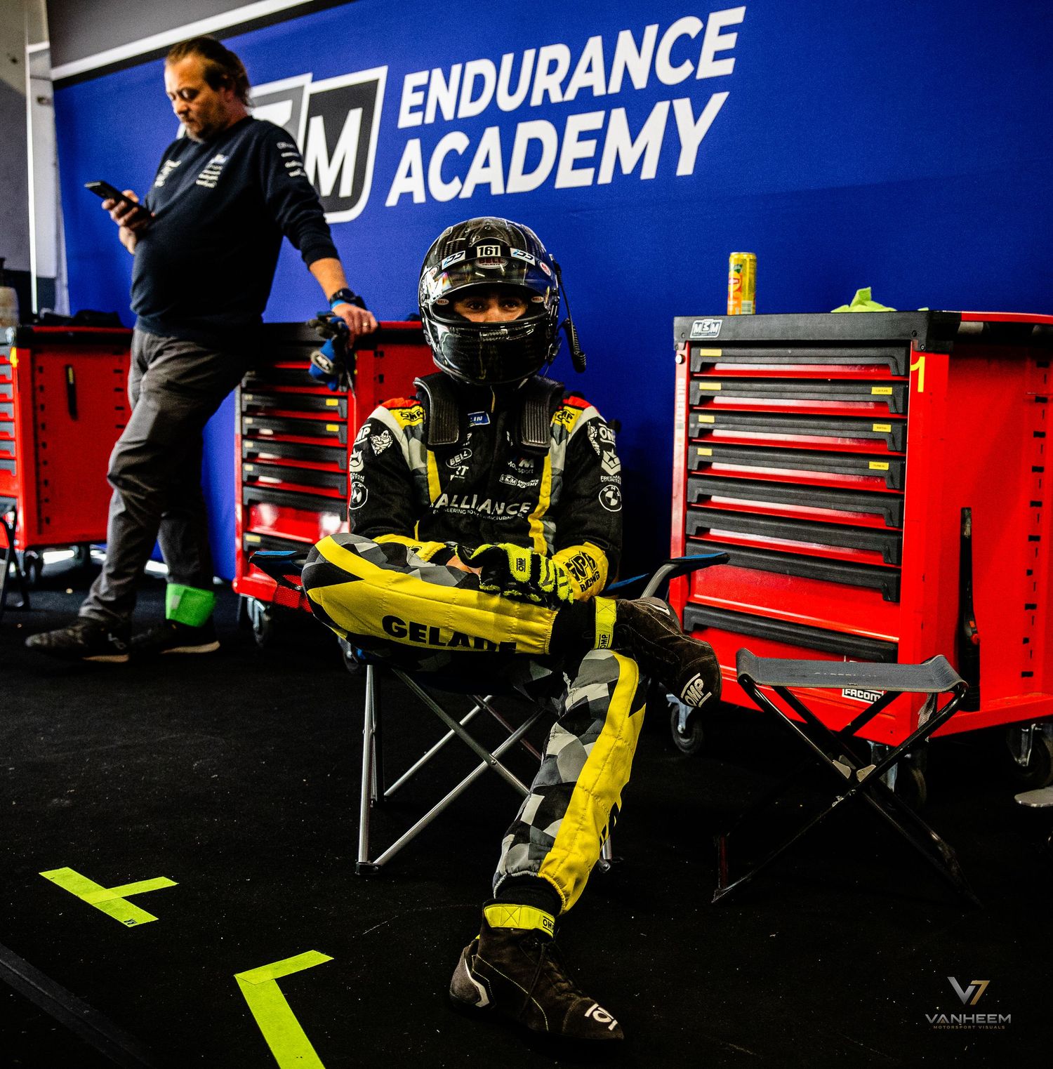A young racing driver in yellow gear sits in a garage at the Endurance Academy motorsport facility.