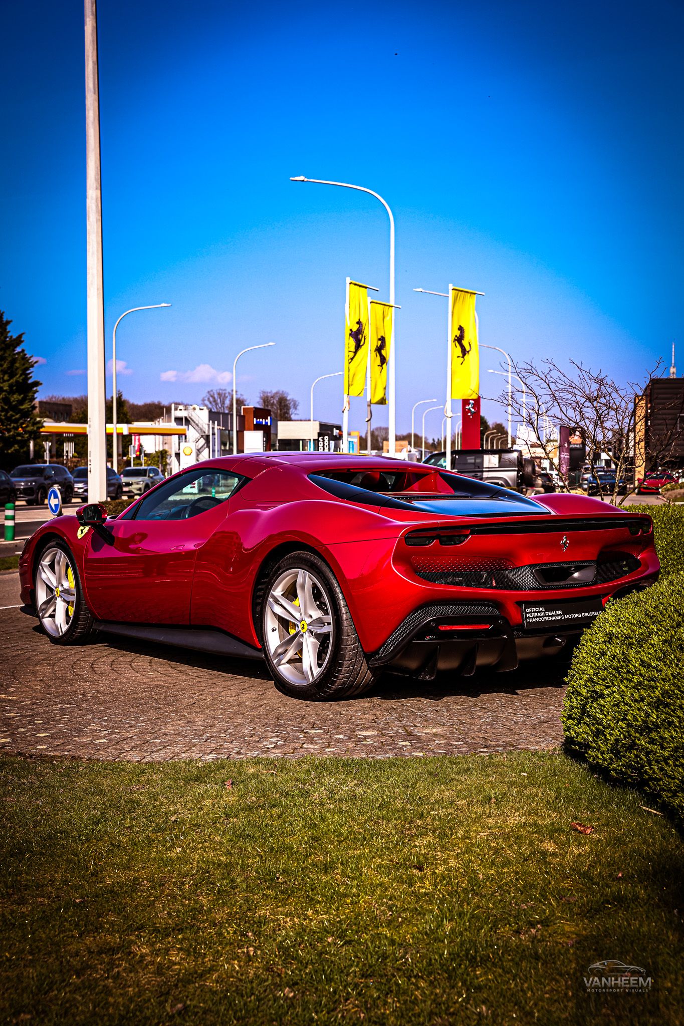 Red Ferrari SF90 Stradale parked on display with Ferrari flags in the background.