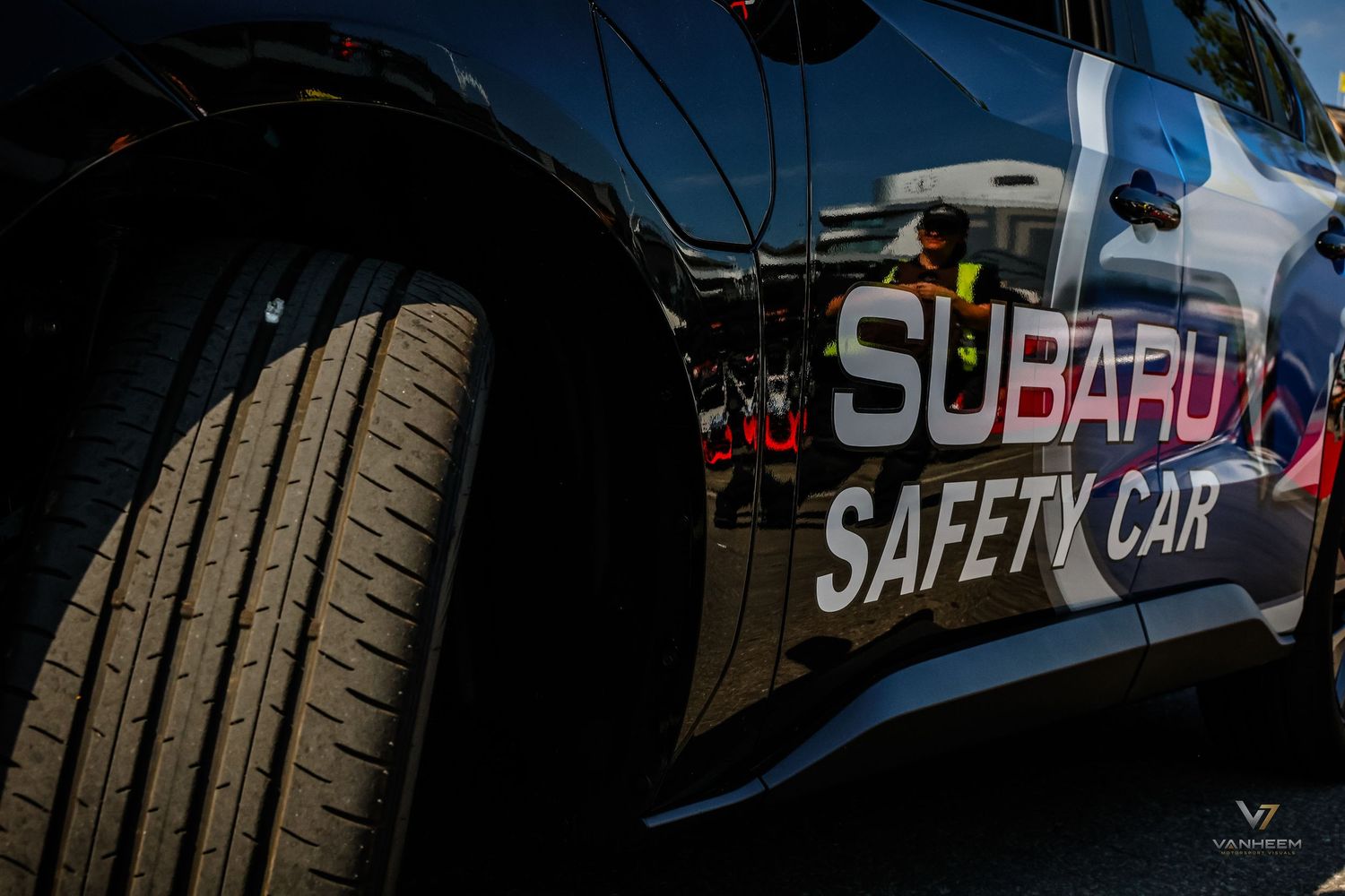 Close-up of a Subaru Safety Car door panel with logo and tire visible at a motorsport event.