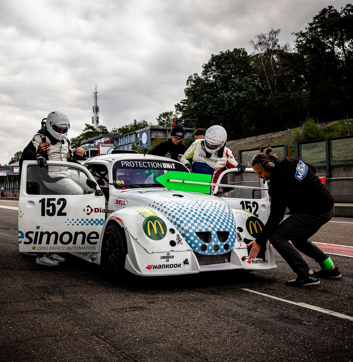 Race car #152 with McDonald's sponsorship being pushed by crew members in pit lane during a motorsport event.