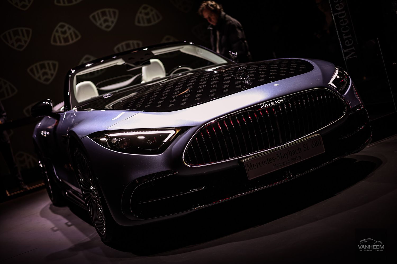 High-end luxury sports car displayed in moody dark lighting at auto exhibition.