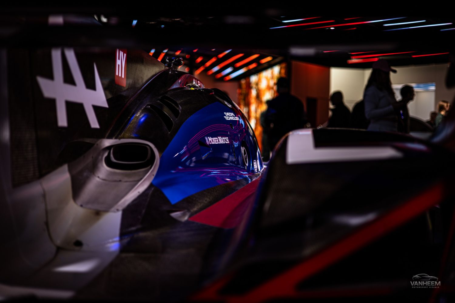 Neon red and blue lighting illuminates a dark gaming setup with multiple monitors and gaming peripherals.