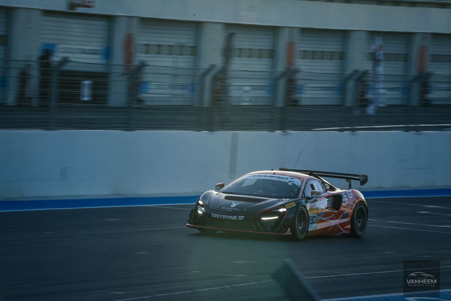 Black racing car drifting on a racetrack with motion blur effect during competitive motorsport event.