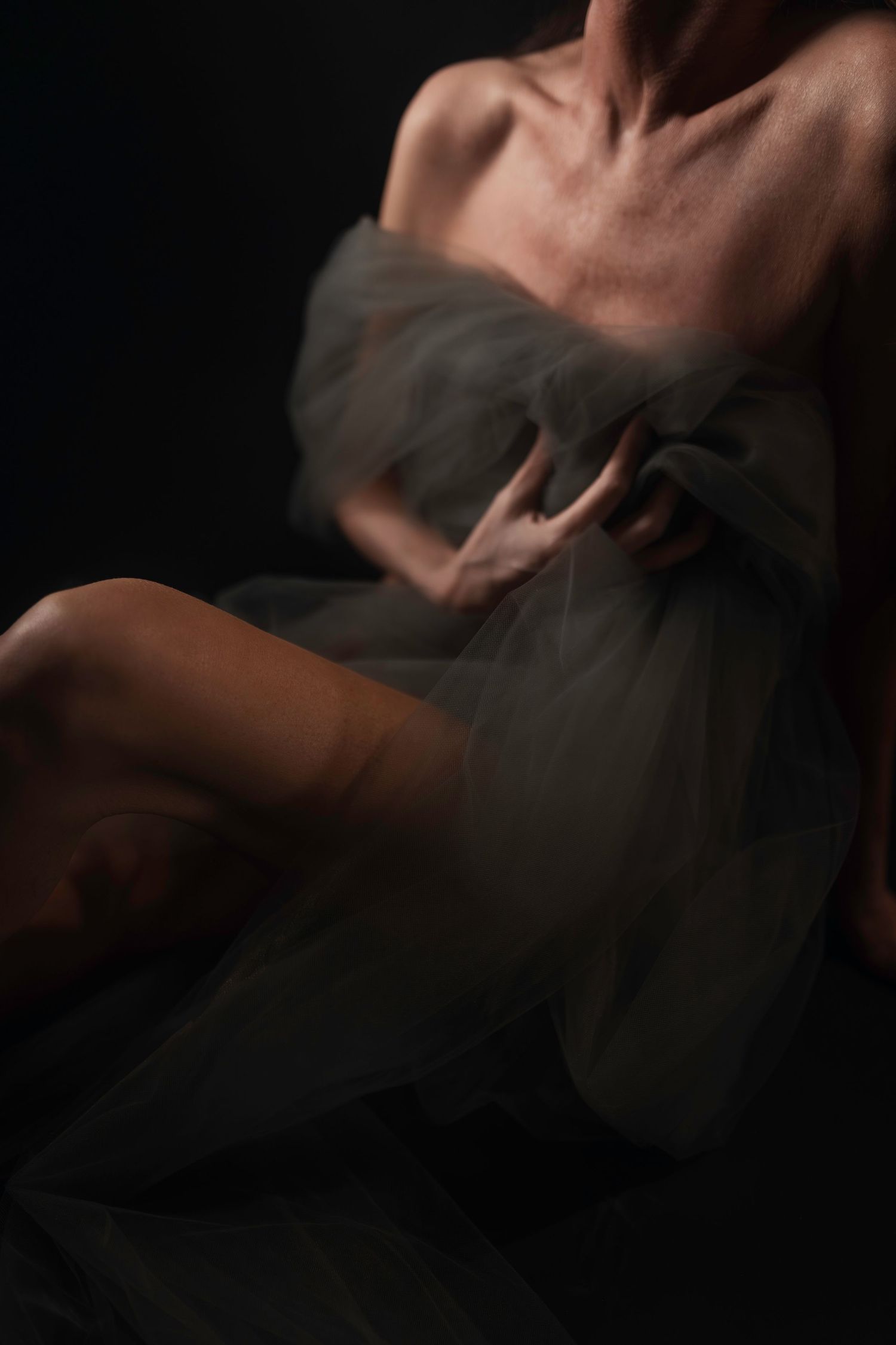 Woman draped in grey tulle with dramatic lighting, detailed boudoir photo, DFW boudoir photography by Lock & Key Fort Worth.