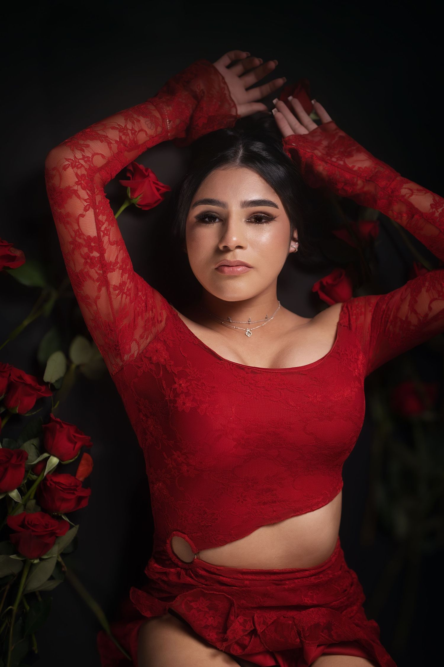 Woman in red lace top surrounded by roses, boudoir portrait photographer serving Dallas, Texas.