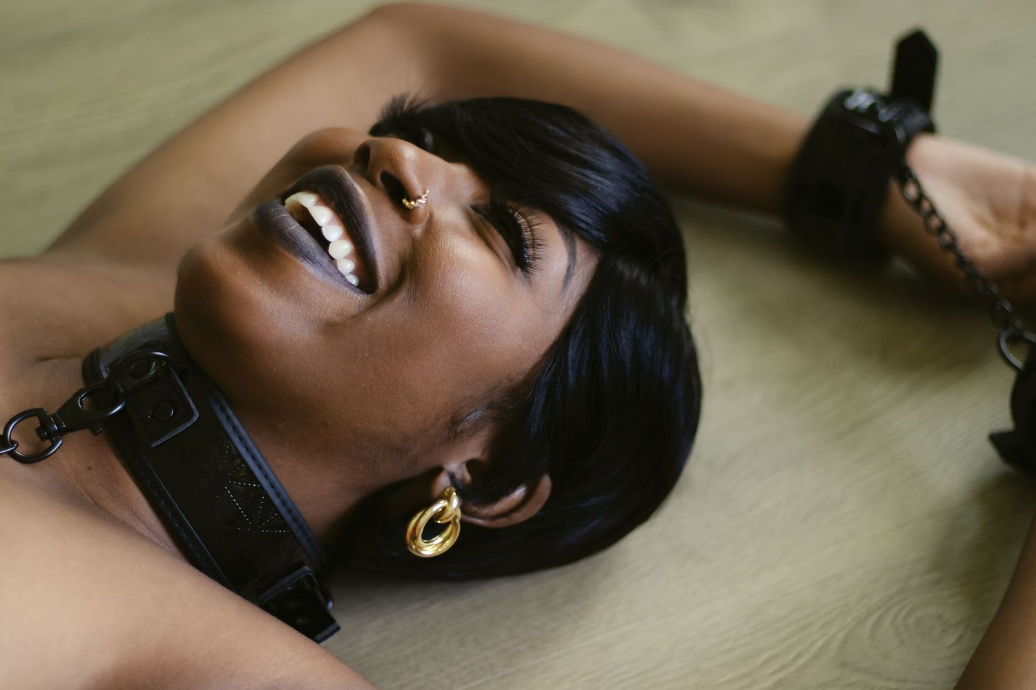 Woman in collar and handcuffs laughing in a bold playful boudoir session — Dallas Fort Worth boudoir photographer.