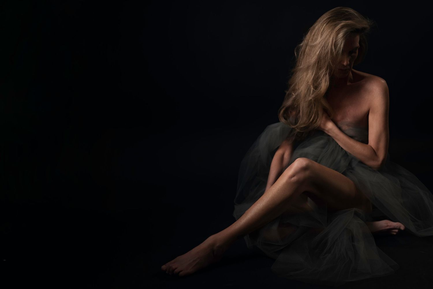 Dallas-Fort Worth boudoir photo of woman in grey sheer wrap, knees pulled in face downward — emotional fine art boudoir photography.