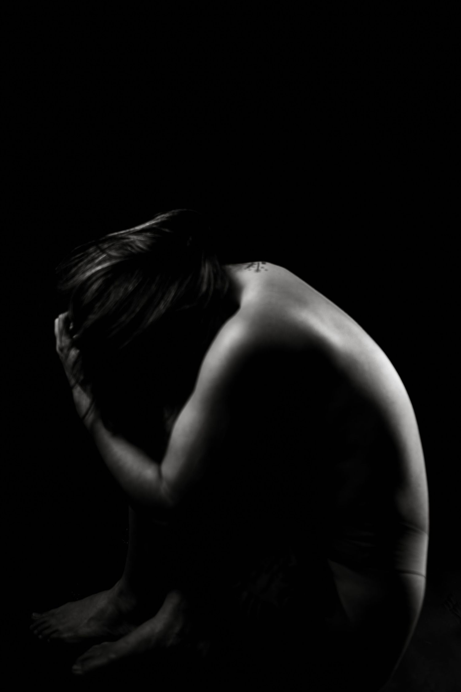 Moody black and white boudoir photo created by a DFW boudoir photographer highlighting vulnerability and feminine form.