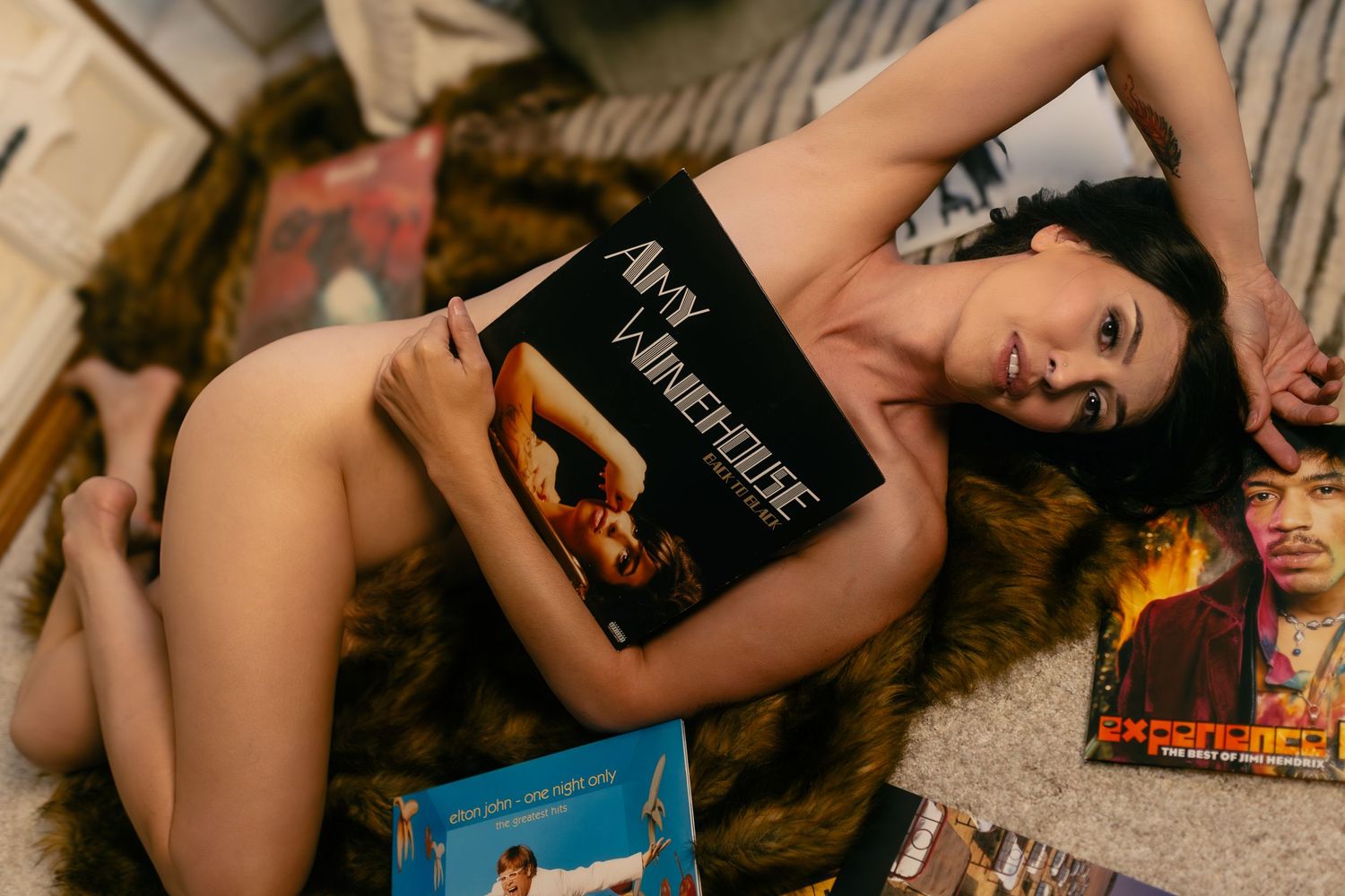 Woman poses with vinyl records on a fur blanket in a DFW boudoir session with Lock and Key Photography.
