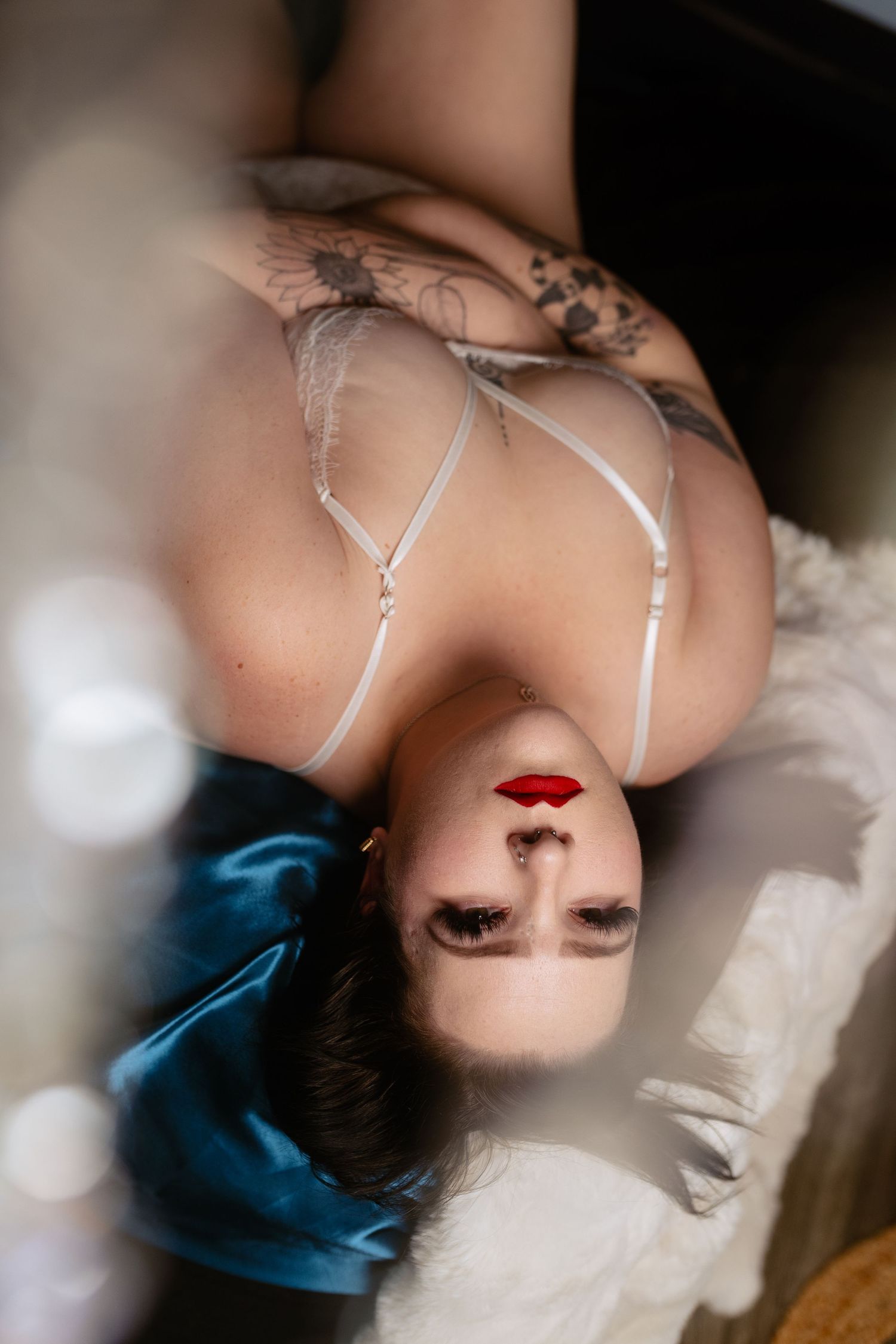 Woman lying on her back on teal satin with dramatic eye makeup —Dallas boudoir photography Lock & Key