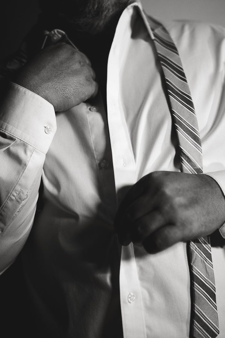 A man unbottons his dress shirt during a Fort Worth couples boudoir session with boudoir photographer, Katy Rohm.