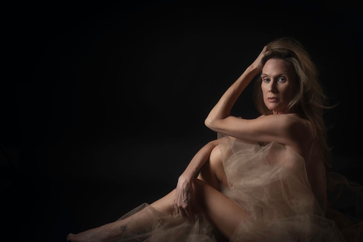 Mature woman wrapped in sheer tulle, luxury boudoir photography serving Dallas, TX.