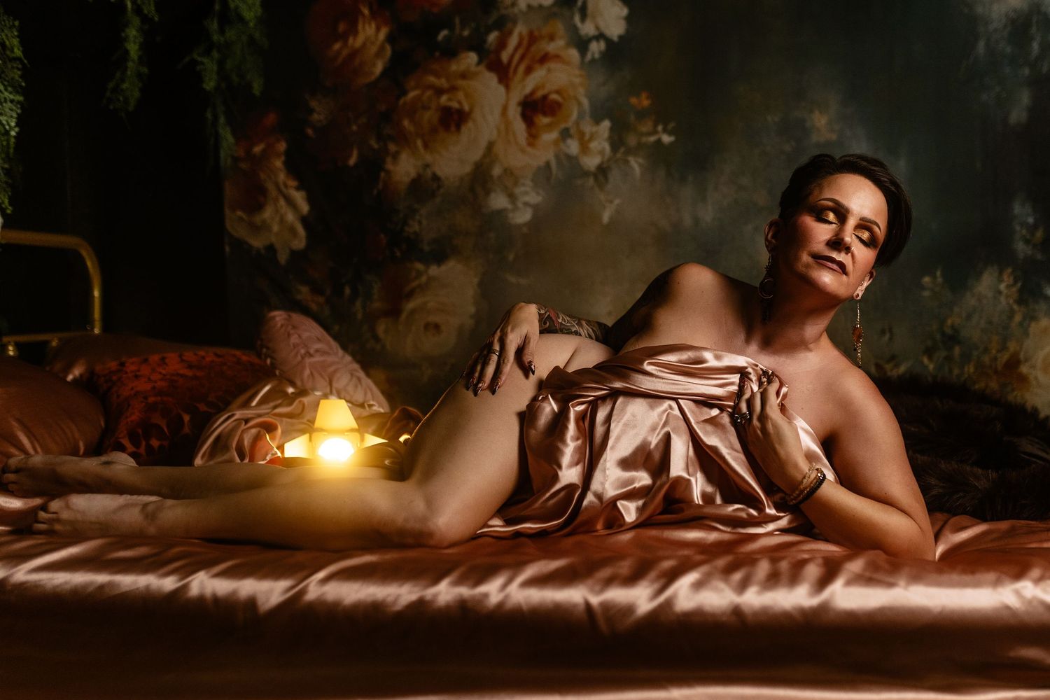 Woman over 40 laying on satin bedding in a dramatic atmospheric boudoir session— Dallas boudoir photography for women over 40.