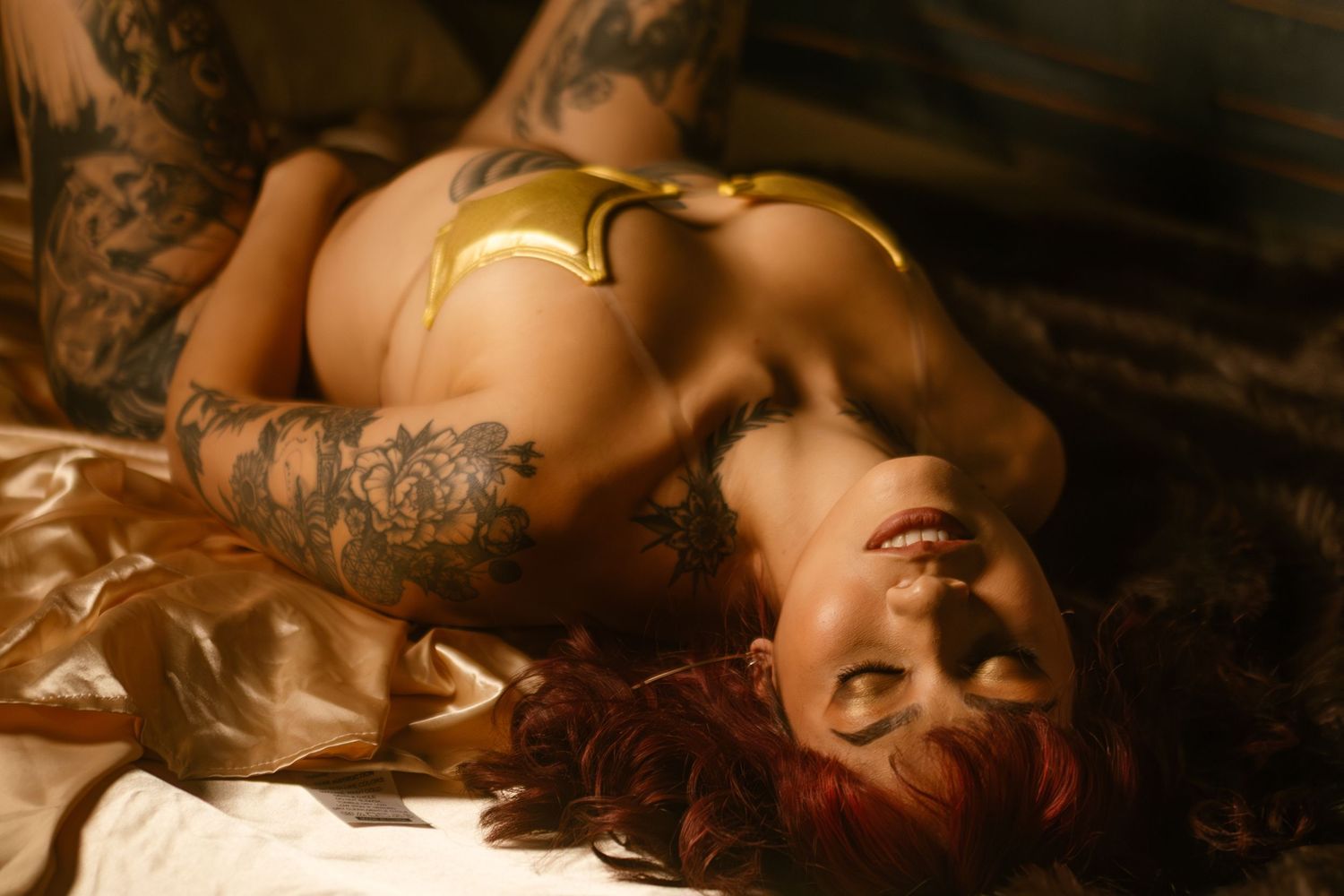 Fort Worth boudoir photography with tattooed woman in golden lingerie, glowing in warm light at Lock & Key Photography.