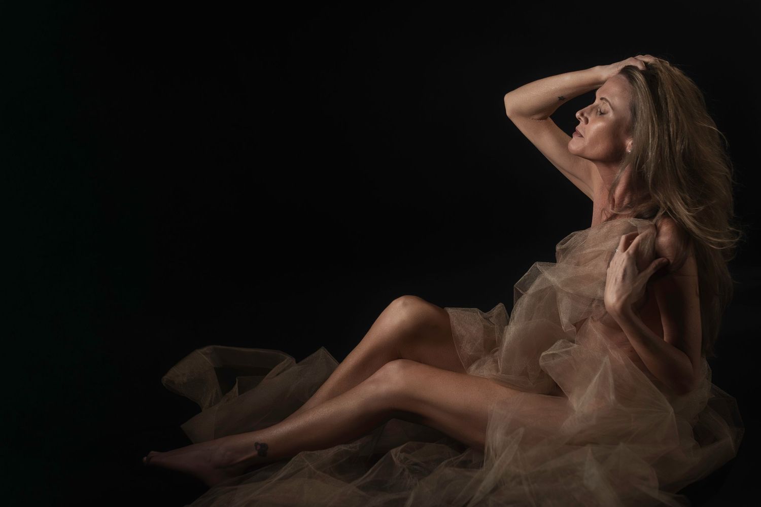 Woman in sheer tulle wrap posed against black backdrop, boudoir photography by Lock & Key Photography Fort Worth