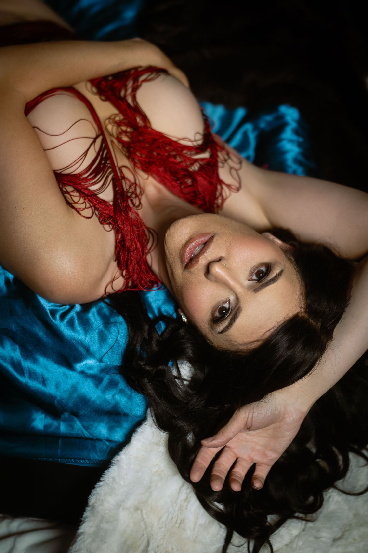 Woman in red lingerie lying on teal satin in a dramatic boudoir session — DFW boudoir photographer, Lock & Key.