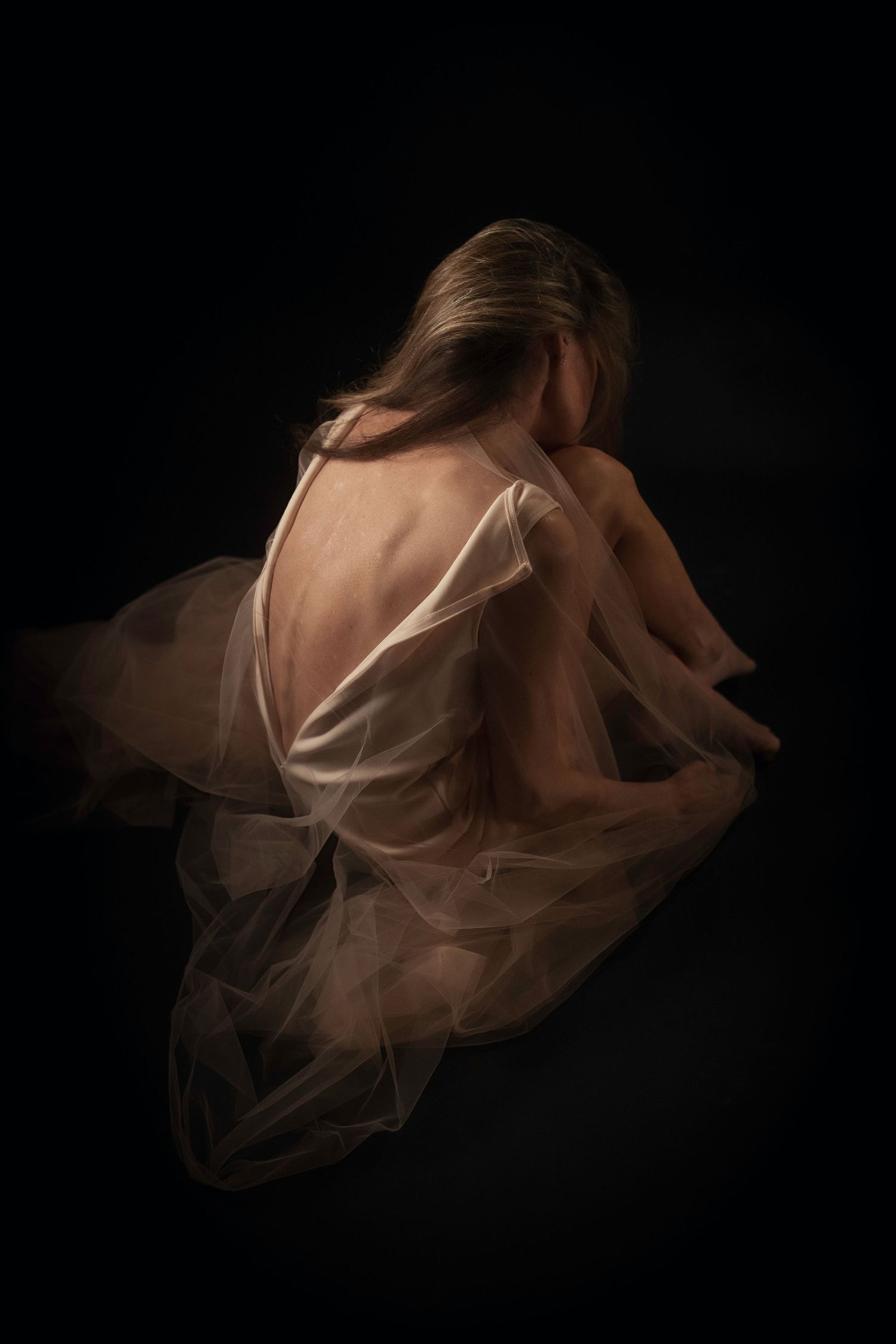 DFW boudoir portrait of woman dropped in sheer ivory tulle, head bowed— introspective fine art boudoir for women over 40 in North Texas.
