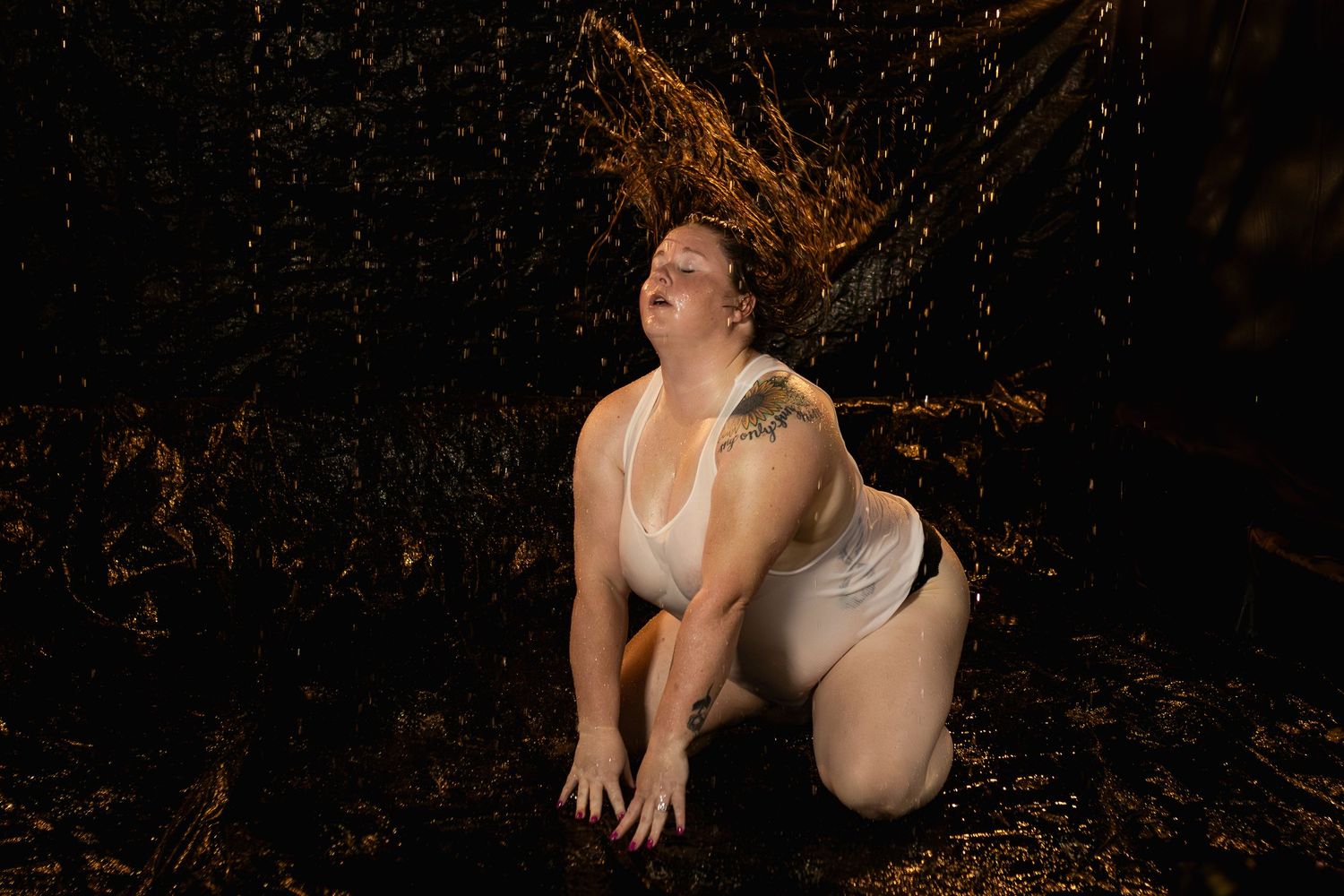 Woman kneeling in water in rain room dramatic pose, fine art boudoir photography Fort Worth TX