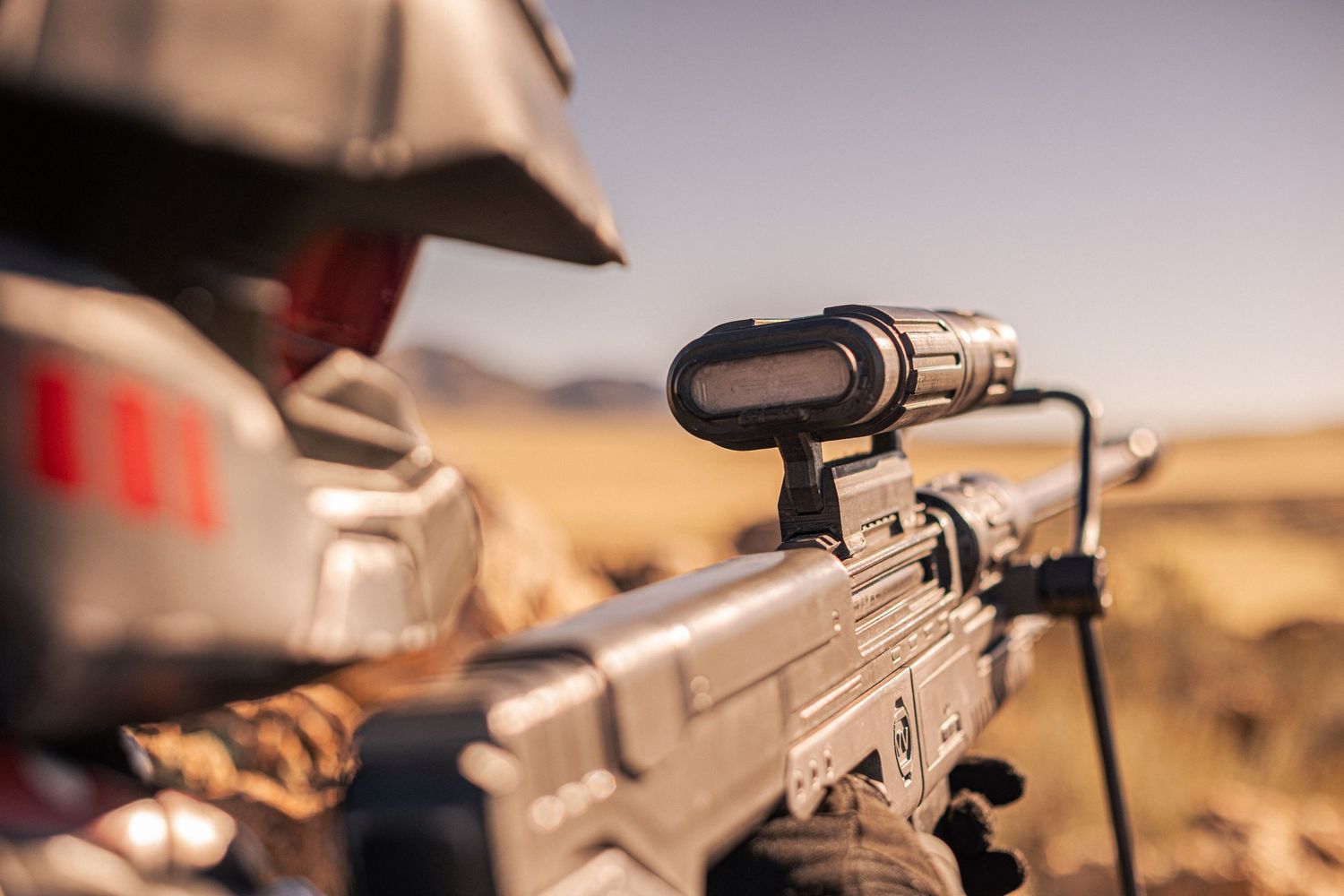Close-up of sci-fi sniper rifle with scope in desert setting cosplay photography.