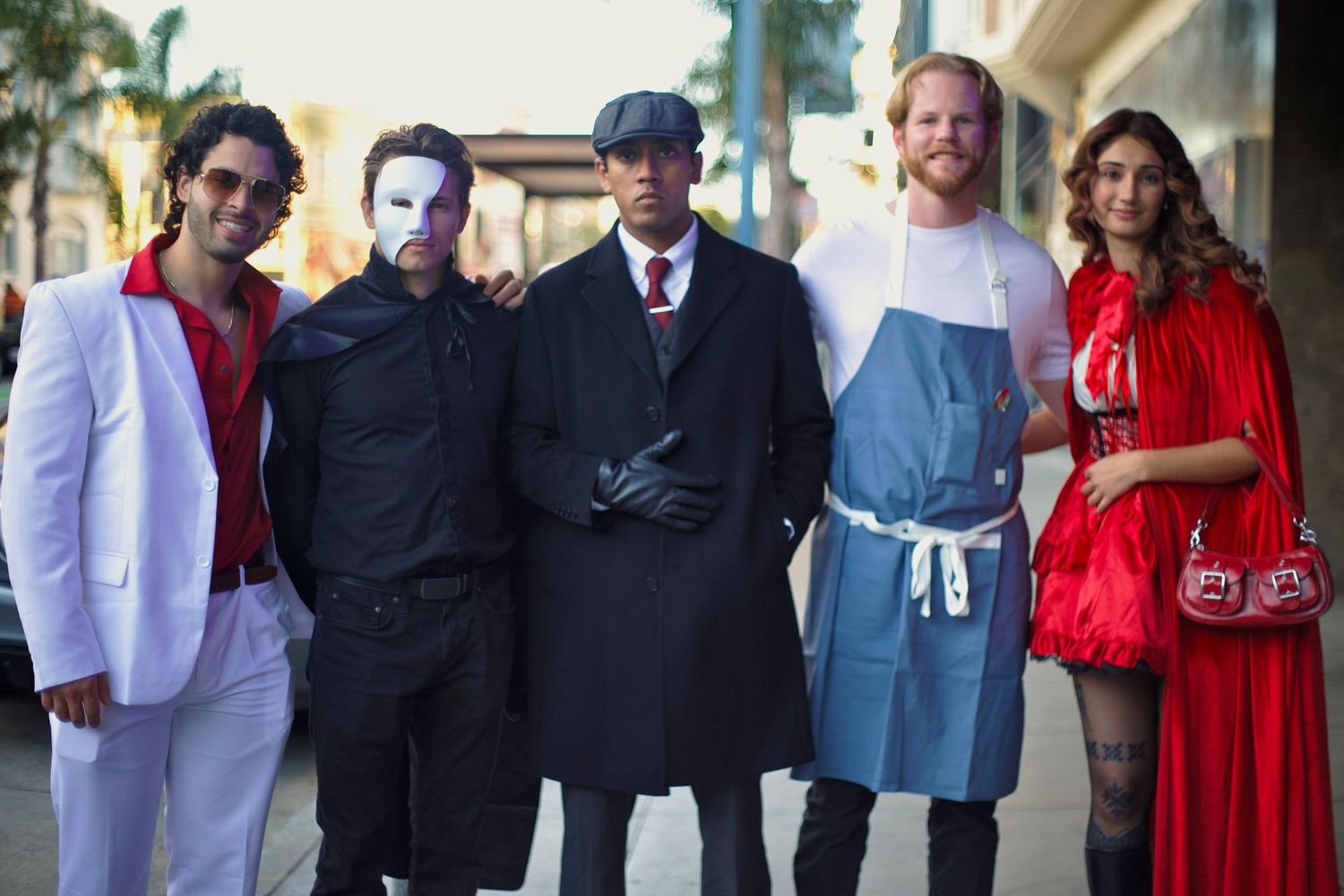 Group of five friends posing in Halloween costumes including Phantom of the Opera and Little Red Riding Hood.