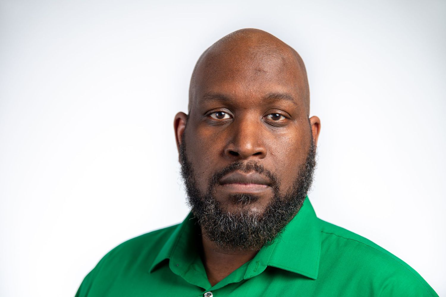 Bald man with a beard wearing a green shirt against a white background.