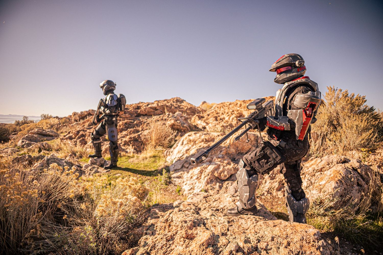 Two Halo ODST cosplayers in full armor stand on rocky terrain aiming weapons.