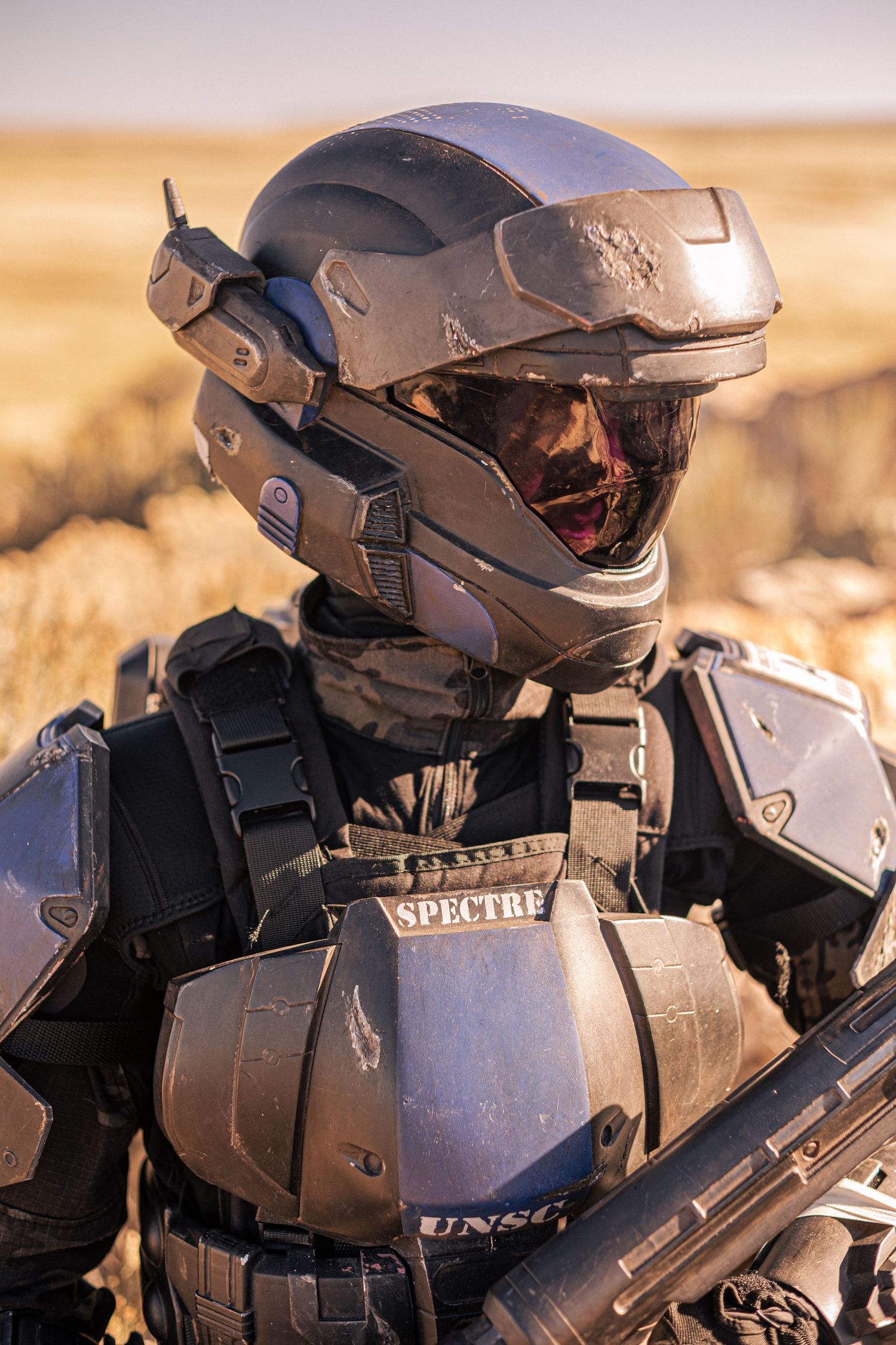Halo ODST cosplayer in detailed SPECTRE armor suit and helmet poses in desert landscape.