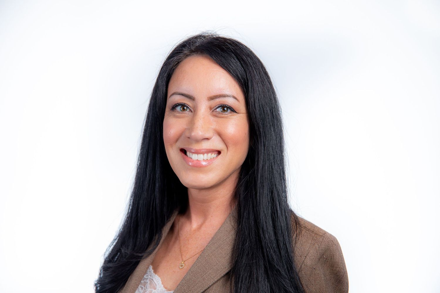 Professional headshot of a smiling woman with long black hair wearing a tan blazer on a white background.