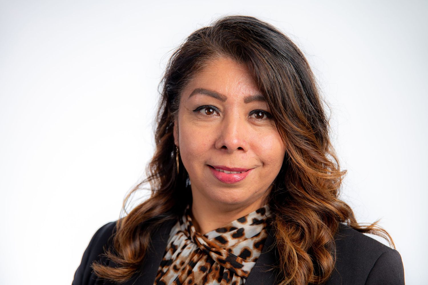 Professional headshot of woman with dark hair wearing leopard print scarf and black blazer.