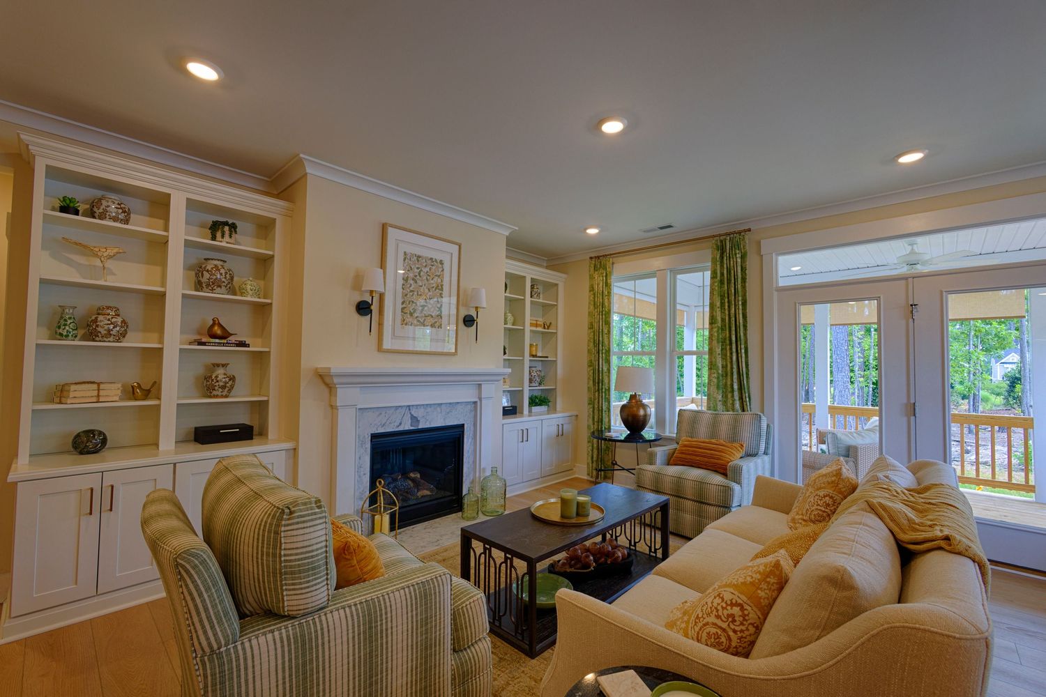 Bright living room with white built-in bookshelves, fireplace, striped furniture, and French doors to a deck.Richmond, Virginia.