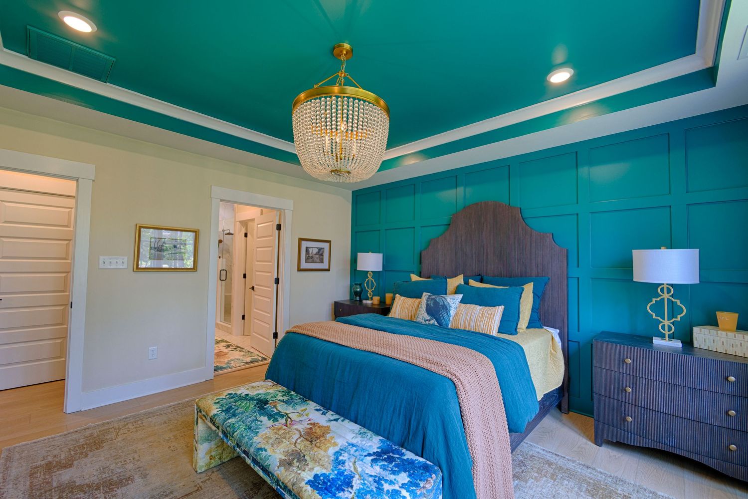 Bold teal bedroom with tray ceiling, chandelier, upholstered headboard, and accent bench.Richmond, Virginia.