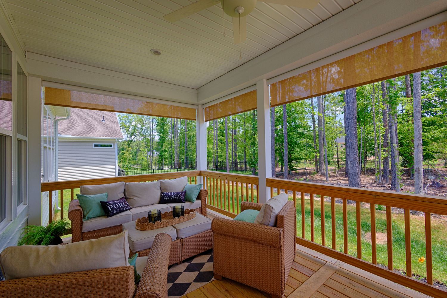 Screened porch with wicker furniture, wood ceiling, and lush wooded backyard views.Richmond, Virginia.