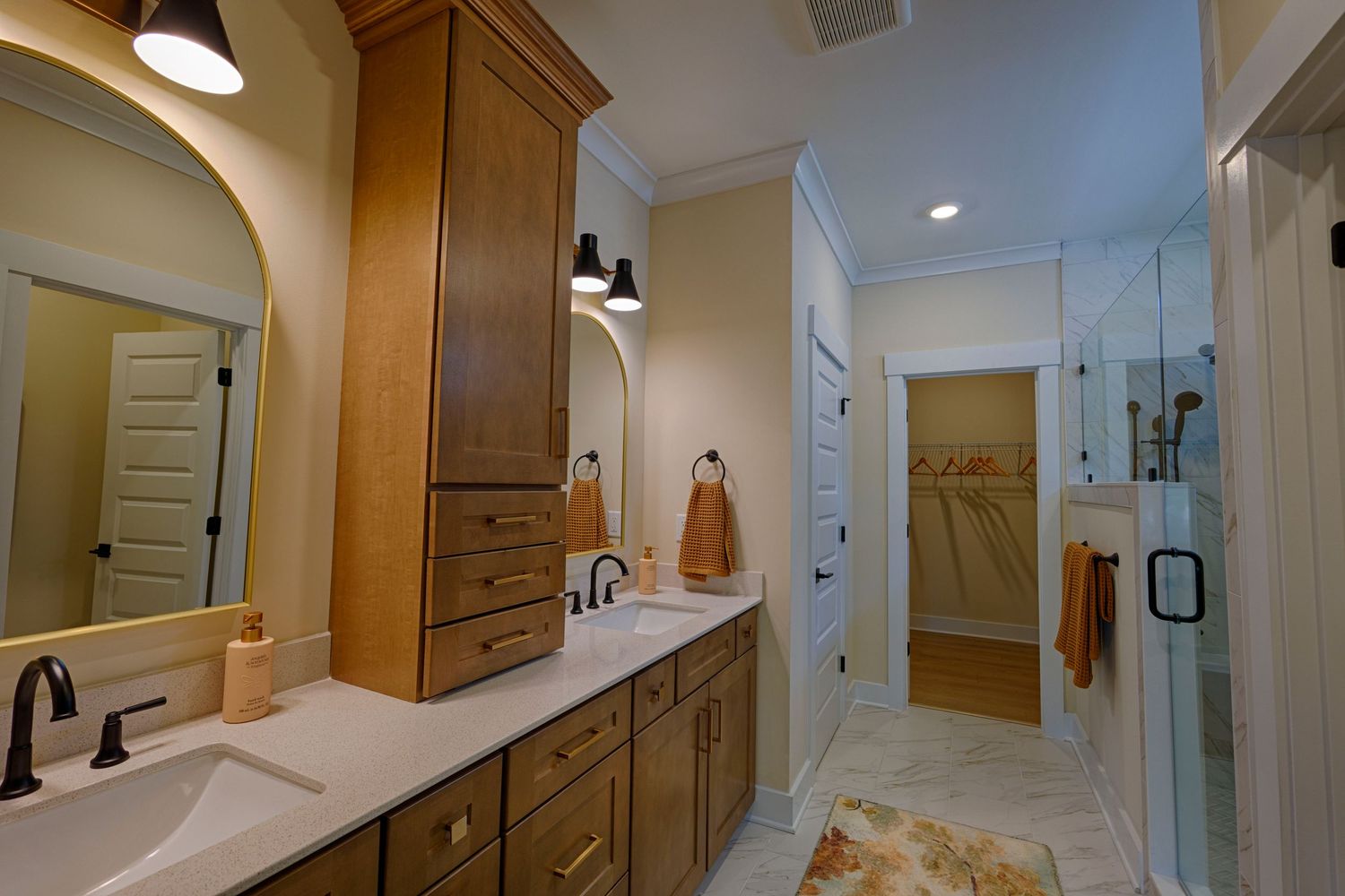 Elegant master bathroom with wood cabinetry, dual sinks, white quartz countertops, and a glass walk-in shower.Richmond, Virginia.