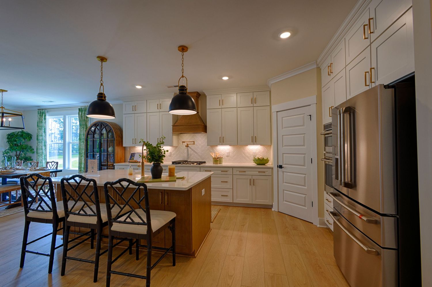 Modern kitchen with white cabinetry, wood island, black pendant lights, and stainless steel appliances on light hardwood floors.Richmond VA