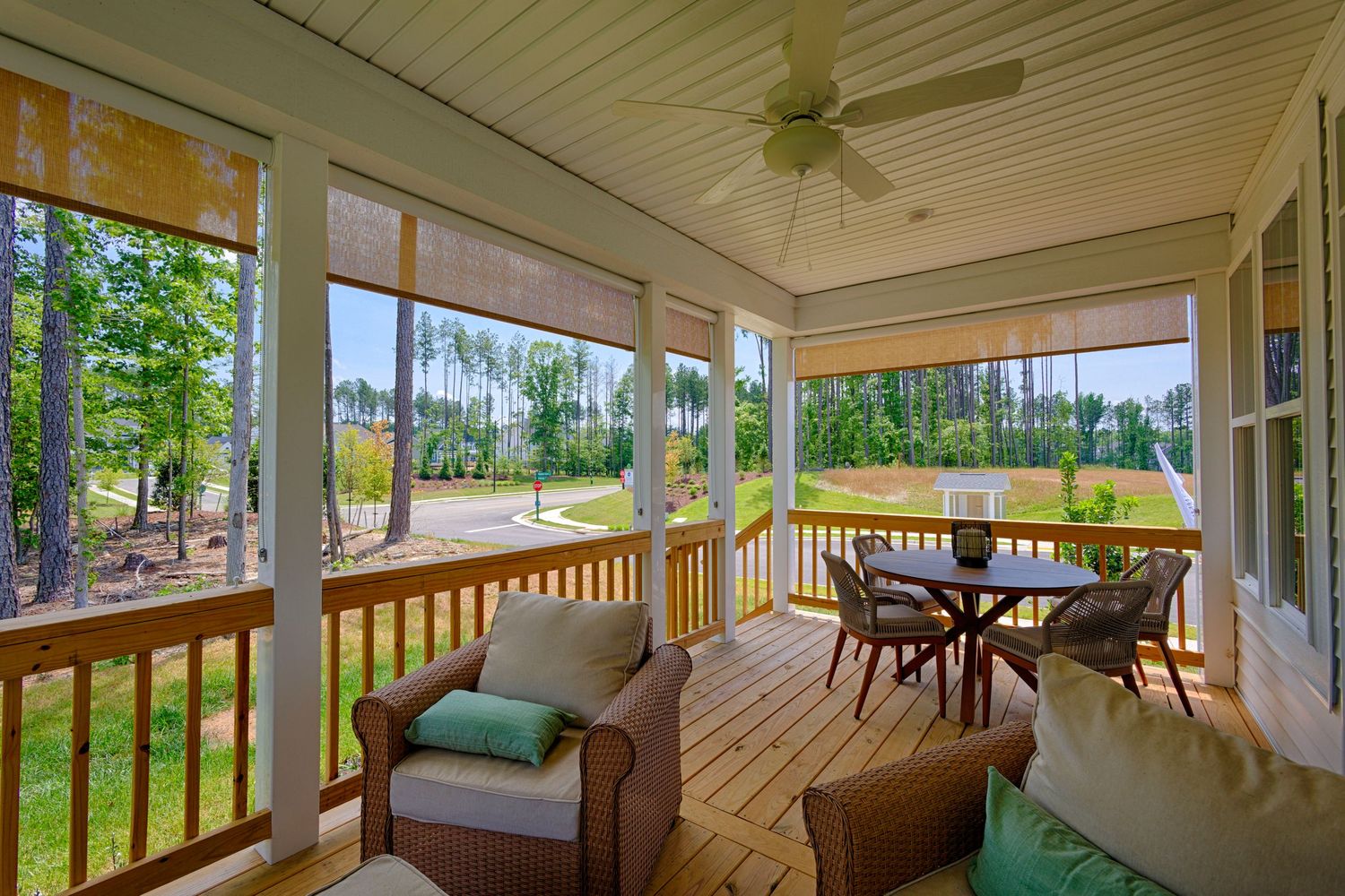 Screened porch with ceiling fan, wicker furniture, dining table, and scenic backyard views surrounded by trees.Richmond, Virginia.
