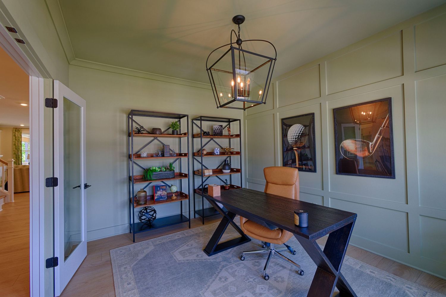Elegant home office with dark wood desk, metal shelving units, lantern chandelier, and sage green wainscoting walls.Richmond VA