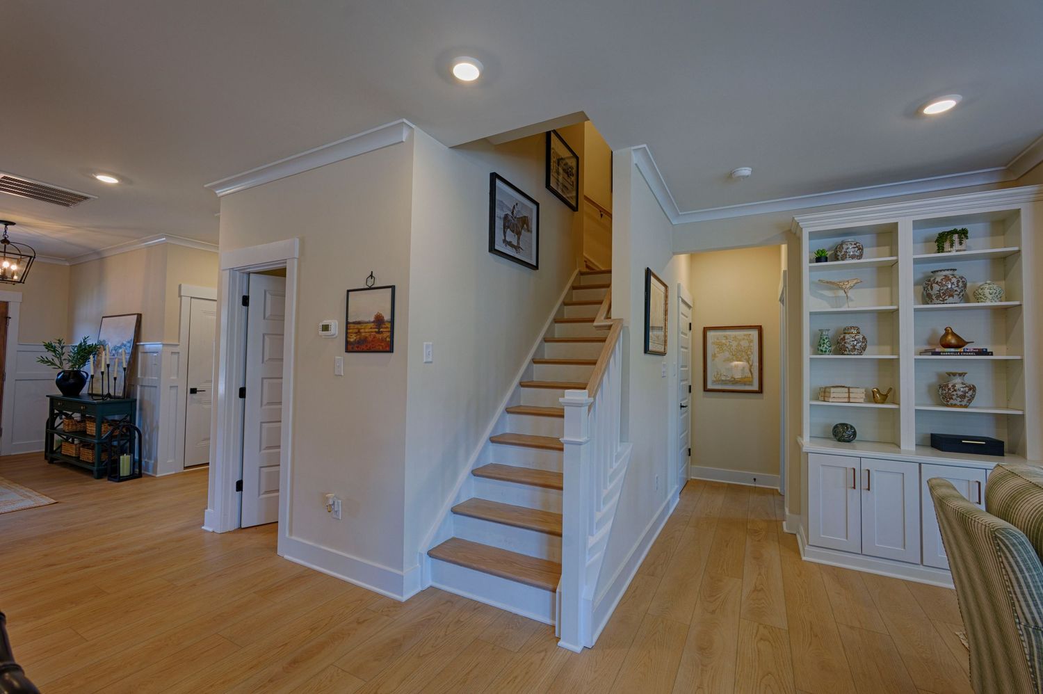 Bright home interior featuring staircase, built-in white shelving, and light hardwood floors.Richmond, Virginia.