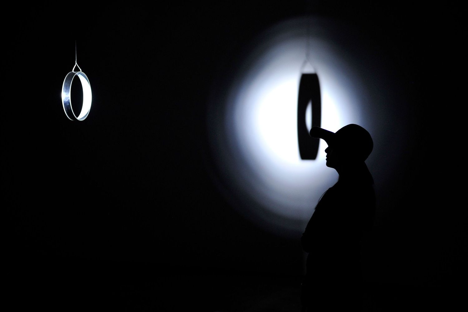 Silhouette of a boxer near a punching bag illuminated by a bright spotlight in a dark gym.