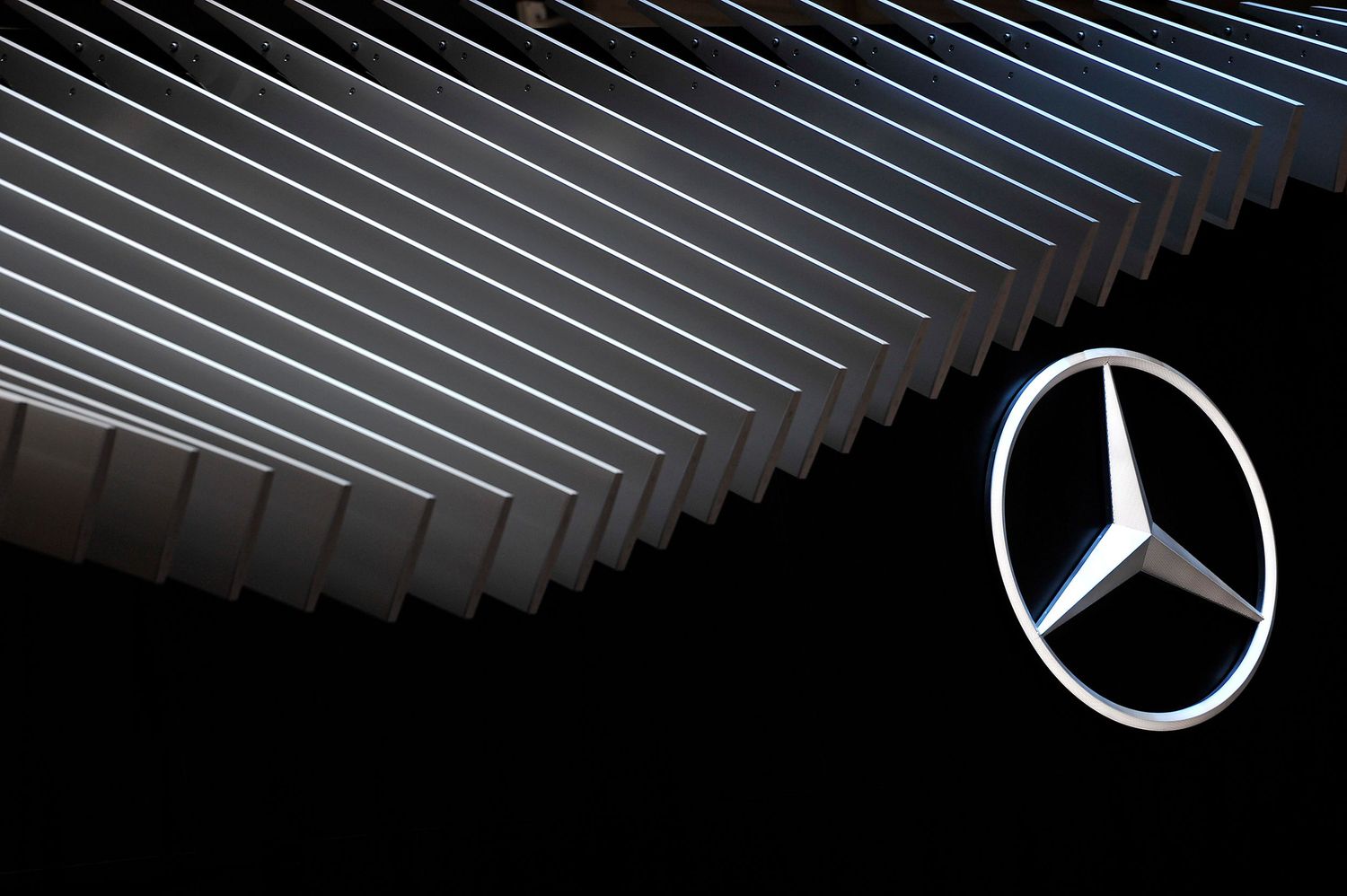 Illuminated Mercedes-Benz three-pointed star logo against dramatic geometric architectural lines.