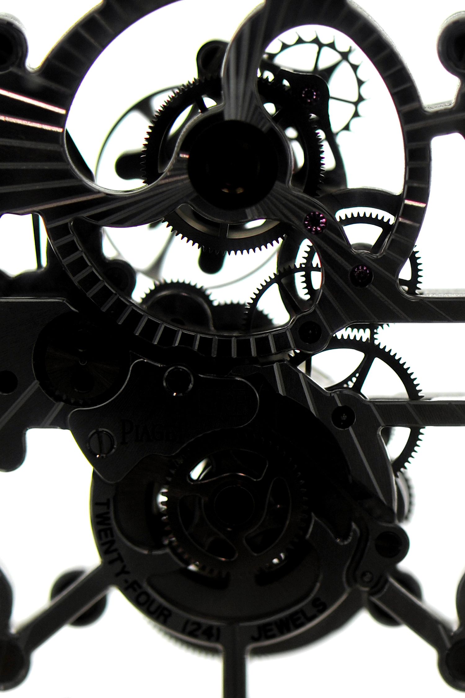 Close-up of intricate black clock gears and mechanical movement parts on white background.