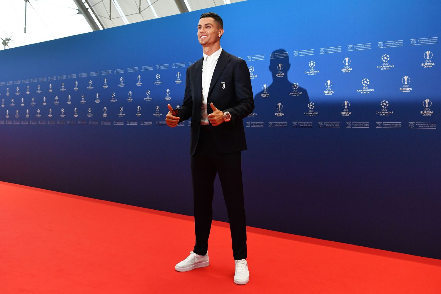 Cristiano Ronaldo in black suit posing on red carpet at UEFA Champions League awards ceremony.