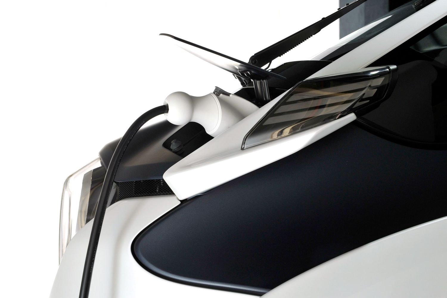 Close-up of white and black Toyota electric vehicle charging port with cable connected.