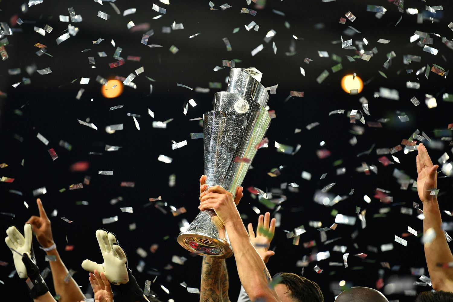 Athletes raise a trophy in triumph amid a shower of confetti during a championship celebration.
