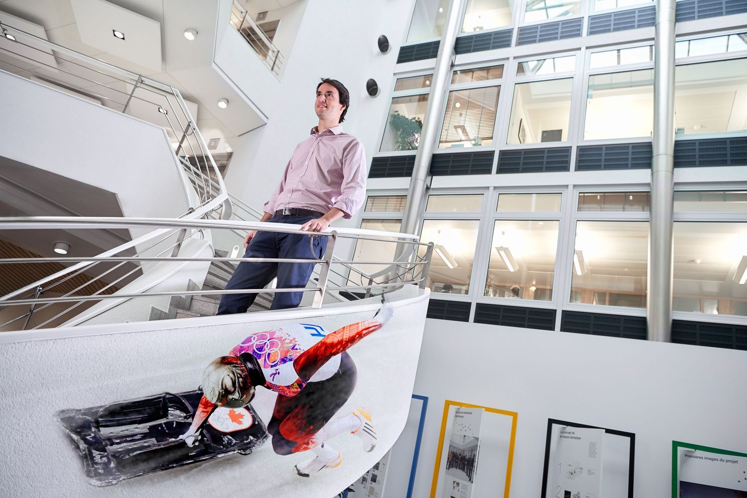 Man standing on modern white spiral staircase at at IOC headquaters.