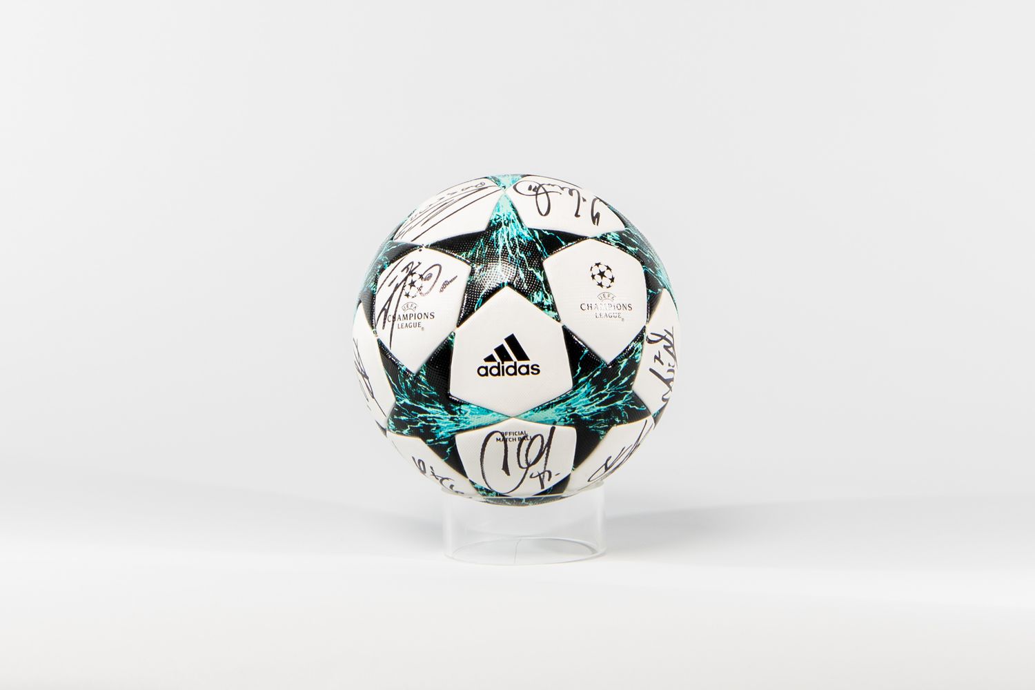 Adidas UEFA Champions League official soccer ball with player autographs on white background.