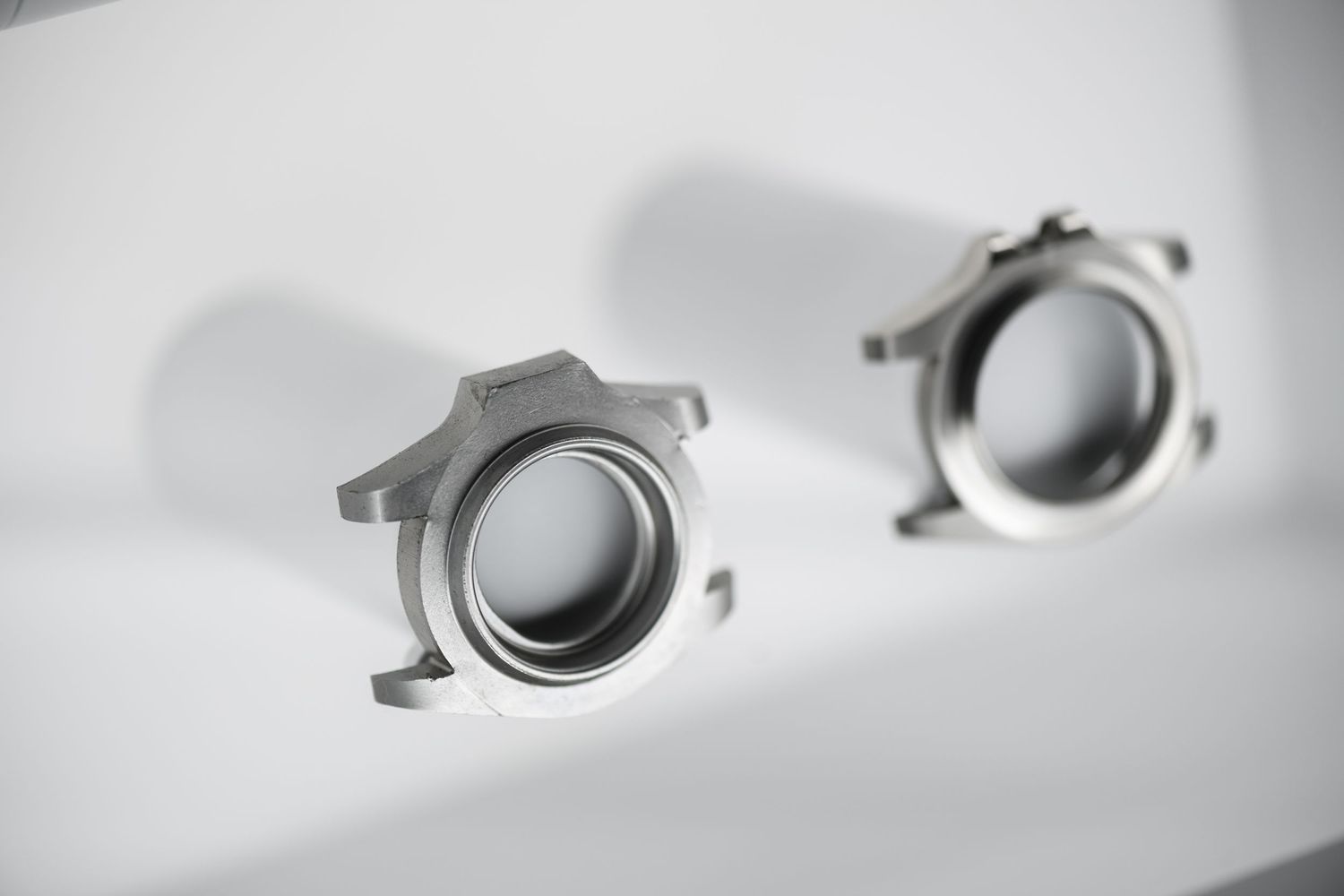 Two precision machined aluminum connector fittings on a clean white surface.