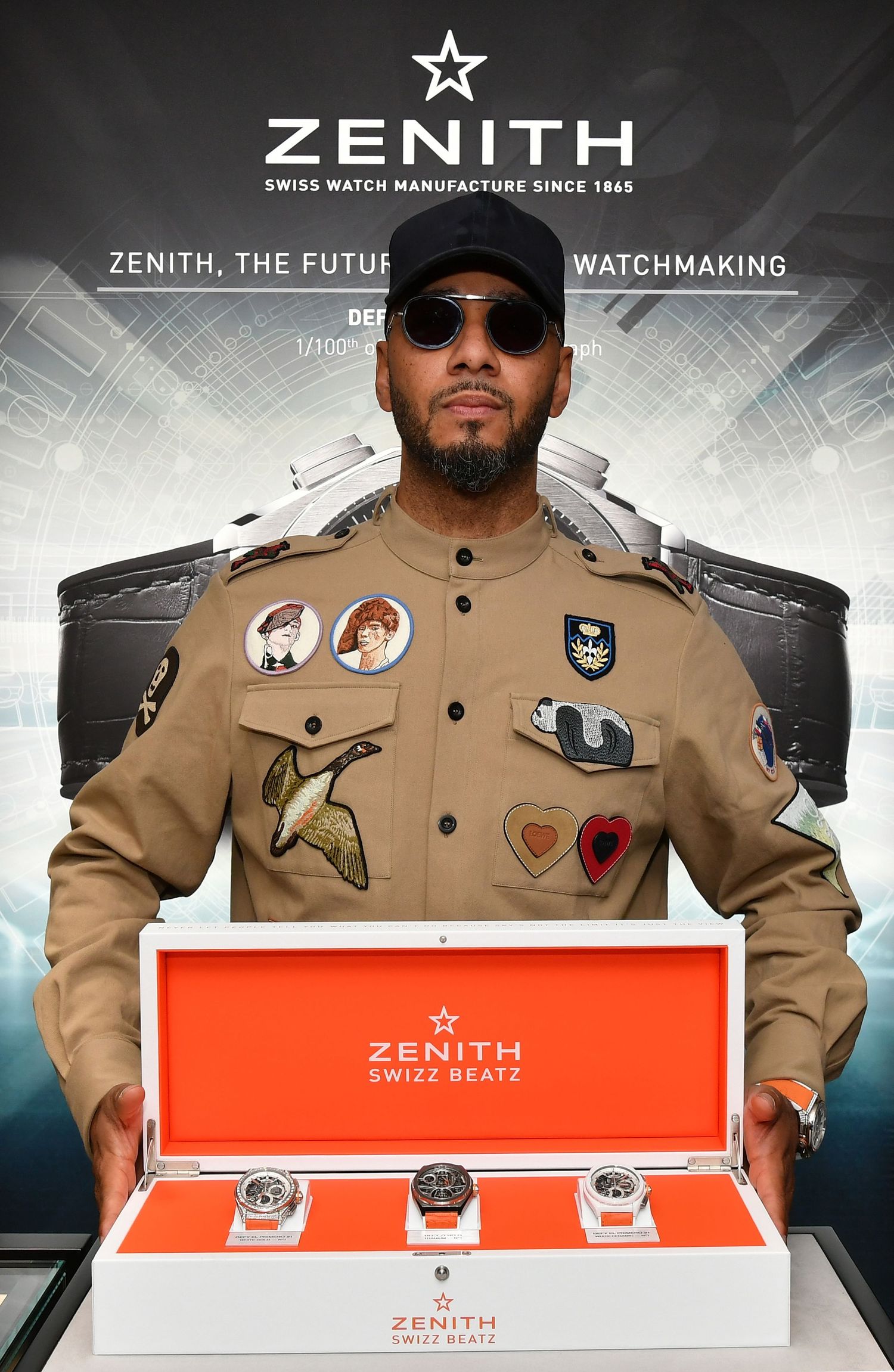 Swizz Beatz presenting Zenith Swiss watch collaboration collection in orange display box at event.